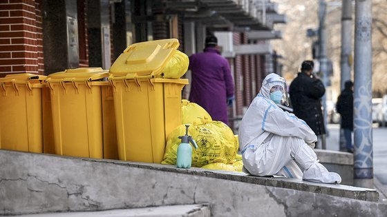 지난 19일 베이징 거리 한가운데 방역복을 입은 작업자가 주저앉아 있다. AFP=연합뉴스<br>
