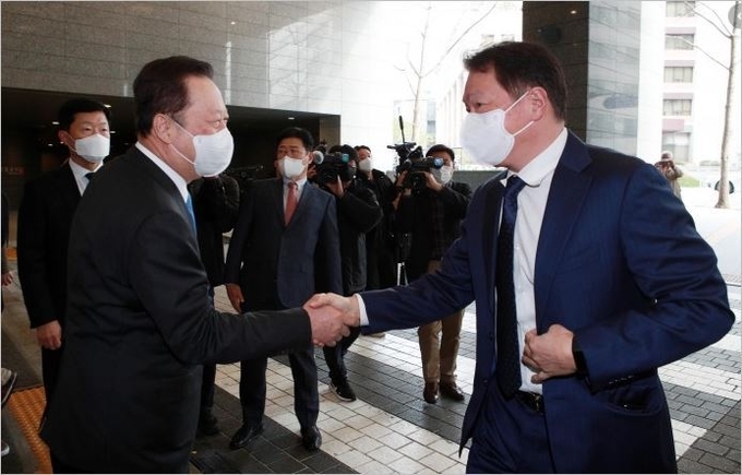 악수하는 박용만 전임회장(좌)과 최태원 신임회장(우)